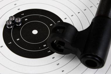 Ateş ve pnömatik silah. Tahta bir masada kurşun mermi ile kalkan ve hits. Karanlık arka plan.