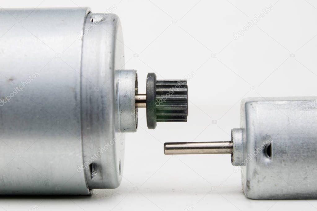 Small electric motor on a white workshop table. Electric drive used in small electrical devices. Light background.
