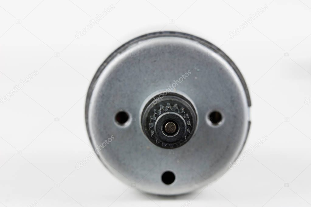 Small electric motor on a white workshop table. Electric drive used in small electrical devices. Light background.