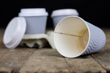 Ahşap bir masa üzerinde bir kağıt kalıp kahve bardağı. Tek kullanımlık yemekler fast food barda kullanılır. Koyu arka plan.