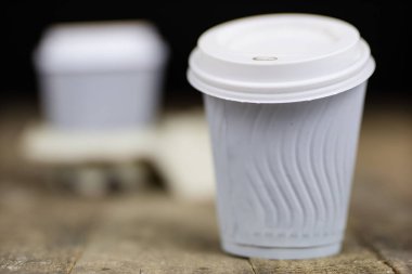 Ahşap bir masa üzerinde bir kağıt kalıp kahve bardağı. Tek kullanımlık yemekler fast food barda kullanılır. Koyu arka plan.