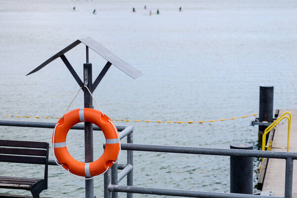 Lifebuoy suspended on the handle at the platform. Lifebuoy accessories for rescuers at the swimming pool. Season of the summer.