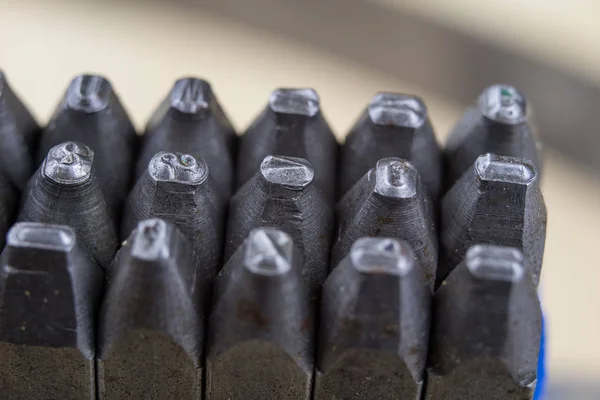 Metal stamps for stamping numbers and letters in metal. Embossed digits in metal. A locksmith workshop.
