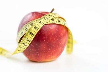 Kırmızı elma ve terzi beyaz bir tabloda bir ölçüsüdür. Olgunlaşmış meyve ve terzi santimetre. Beyaz arka plan.