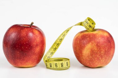 Kırmızı elma ve terzi beyaz bir tabloda bir ölçüsüdür. Olgunlaşmış meyve ve terzi santimetre. Beyaz arka plan.