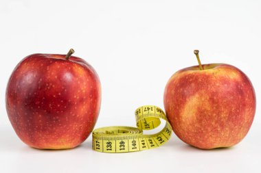 Kırmızı elma ve terzi beyaz bir tabloda bir ölçüsüdür. Olgunlaşmış meyve ve terzi santimetre. Beyaz arka plan.