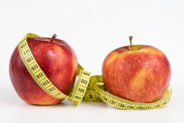 Kırmızı elma ve terzi beyaz bir tabloda bir ölçüsüdür. Olgunlaşmış meyve ve terzi santimetre. Beyaz arka plan.