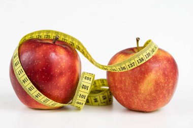 Kırmızı elma ve terzi beyaz bir tabloda bir ölçüsüdür. Olgunlaşmış meyve ve terzi santimetre. Beyaz arka plan.