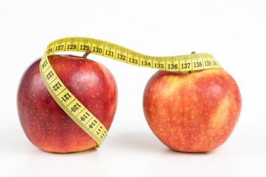 Kırmızı elma ve terzi beyaz bir tabloda bir ölçüsüdür. Olgunlaşmış meyve ve terzi santimetre. Beyaz arka plan.