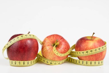 Kırmızı elma ve terzi beyaz bir tabloda bir ölçüsüdür. Olgunlaşmış meyve ve terzi santimetre. Beyaz arka plan.