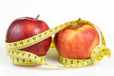 Kırmızı elma ve terzi beyaz bir tabloda bir ölçüsüdür. Olgunlaşmış meyve ve terzi santimetre. Beyaz arka plan.