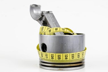 Bir piston bir içten yanmalı motor ve bir terzi ölçü birimi üzerinde beyaz bir tablo. Araba parçaları ve terzi santimetre. Beyaz arka plan.