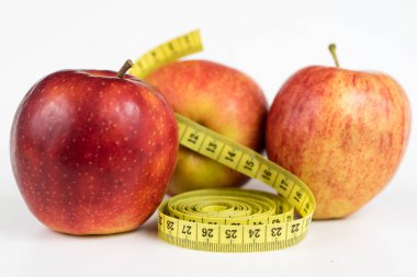 Kırmızı elma ve terzi beyaz bir tabloda bir ölçüsüdür. Olgunlaşmış meyve ve terzi santimetre. Beyaz arka plan.