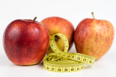 Kırmızı elma ve terzi beyaz bir tabloda bir ölçüsüdür. Olgunlaşmış meyve ve terzi santimetre. Beyaz arka plan.