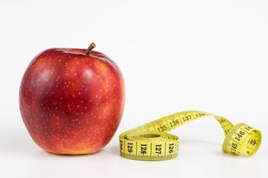 Kırmızı elma ve terzi beyaz bir tabloda bir ölçüsüdür. Olgunlaşmış meyve ve terzi santimetre. Beyaz arka plan.