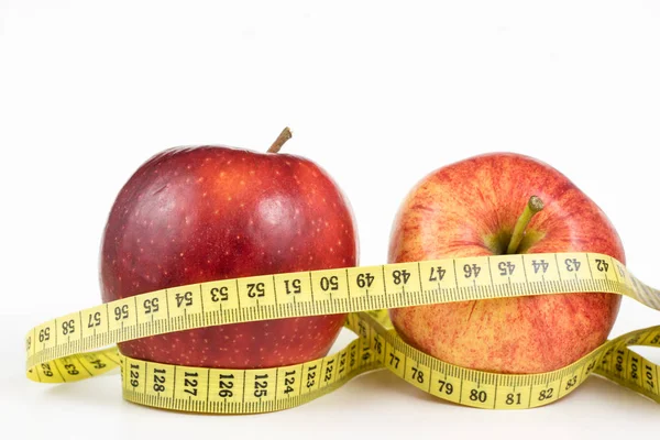 Kırmızı elma ve terzi beyaz bir tabloda bir ölçüsüdür. Olgunlaşmış meyve ve terzi santimetre. Beyaz arka plan.