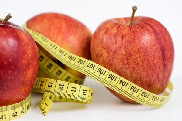 Kırmızı elma ve terzi beyaz bir tabloda bir ölçüsüdür. Olgunlaşmış meyve ve terzi santimetre. Beyaz arka plan.
