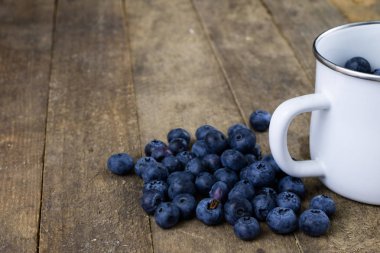 Olgun yaban mersini meyve ahşap mutfak masasında kapsayıcı. Meyve tatlı için hazır. Koyu arka plan.