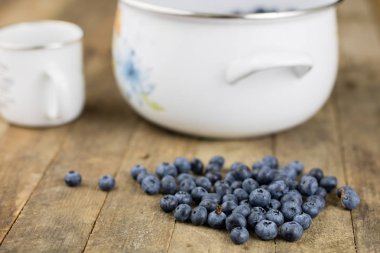 Olgun yaban mersini meyve ahşap mutfak masasında kapsayıcı. Meyve tatlı için hazır. Koyu arka plan.