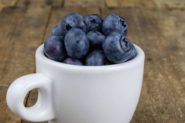 Olgun yaban mersini meyve ahşap mutfak masasında kapsayıcı. Meyve tatlı için hazır. Koyu arka plan.