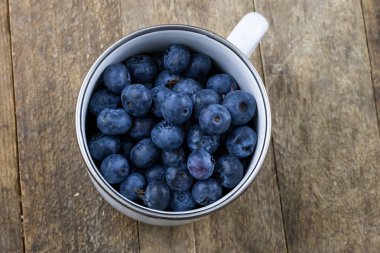 Olgun yaban mersini meyve ahşap mutfak masasında kapsayıcı. Meyve tatlı için hazır. Koyu arka plan.