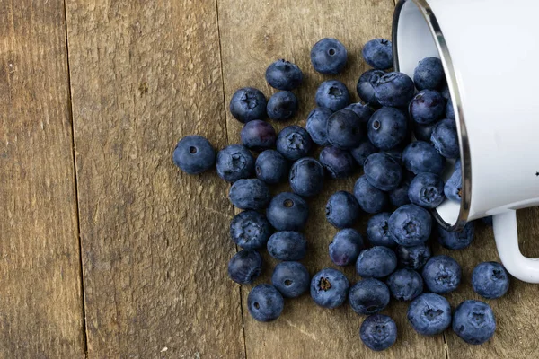 Olgun yaban mersini meyve ahşap mutfak masasında kapsayıcı. Meyve tatlı için hazır. Koyu arka plan.
