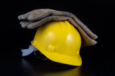 Kask ve bir siyah çalışma masasında iş giysisi. İnşaat işçileri için aksesuarlar. Siyah arka plan.