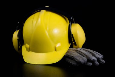 Kask ve bir siyah çalışma masasında iş giysisi. İnşaat işçileri için aksesuarlar. Siyah arka plan.