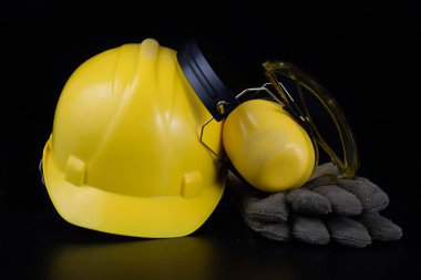 Kask ve bir siyah çalışma masasında iş giysisi. İnşaat işçileri için aksesuarlar. Siyah arka plan.