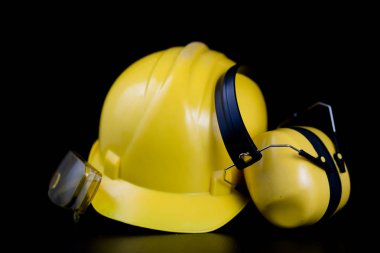 Kask ve bir siyah çalışma masasında iş giysisi. İnşaat işçileri için aksesuarlar. Siyah arka plan.