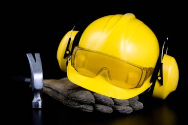 Kask ve bir siyah çalışma masasında iş giysisi. İnşaat işçileri için aksesuarlar. Siyah arka plan.