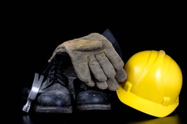 Kask ve bir siyah çalışma masasında iş giysisi. İnşaat işçileri için aksesuarlar. Siyah arka plan.
