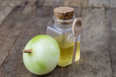 Soğan suyu ve sebzeler üzerinde ahşap bir masa. Ev yapımı şurubu grip tedavisi için. Koyu arka plan.