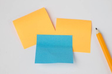 Kalem ve beyaz bir tabloda sticky notes. Notları kaydetmek için ofis aksesuarları. Beyaz arka plan.