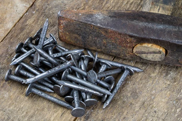 Hammer and nails on a wooden workshop table. Joinery accessories in a DIY workshop. Dark background.