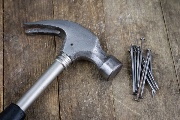 Hammer and nails on a wooden workshop table. Joinery accessories in a DIY workshop. Dark background.