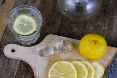 Eski ahşap masa Limonlu soğuk su cam kap. Soğuk içecekler sıcak bir günde. Koyu arka plan.