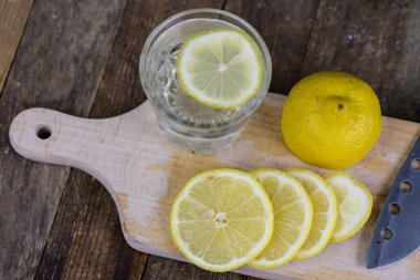 Eski ahşap masa Limonlu soğuk su cam kap. Soğuk içecekler sıcak bir günde. Koyu arka plan.