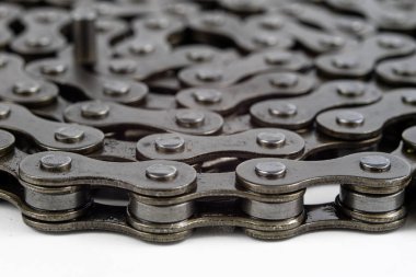 Bisiklet zinciri beyaz bir masa üzerinde düzenlenmiştir. İki tekerlekli parçalar için periyodik servis. Açık arka plan.