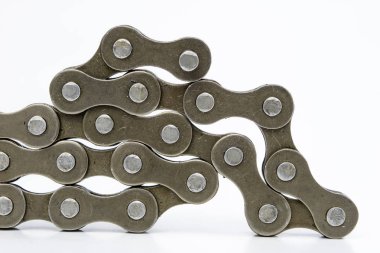 Bisiklet zinciri beyaz bir masa üzerinde düzenlenmiştir. İki tekerlekli parçalar için periyodik servis. Açık arka plan.