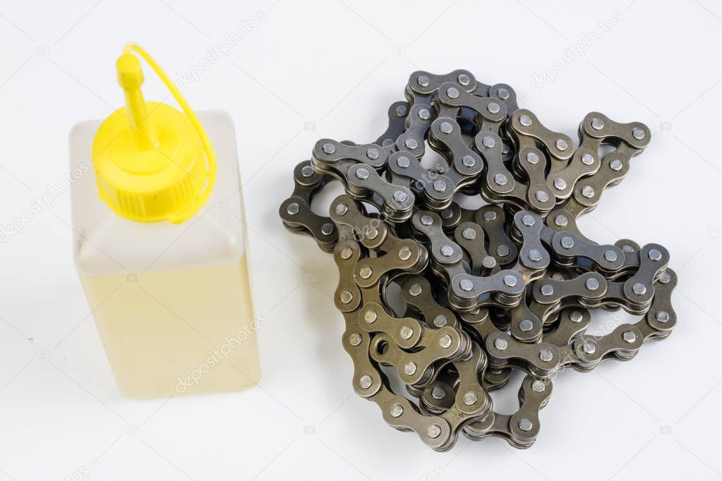 Lubricating the bicycle chain with liquid lubricant. Periodic servicing of parts for two-wheelers. Light background.