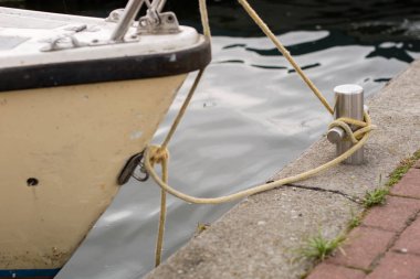 Baba bir halatı ile etrafına sarılmış. Yat limanında demirli tekneler. Yaz sezonu.