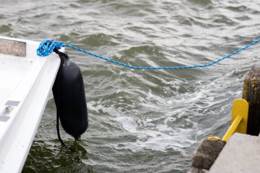 Tamponlar yat tarafında asılı. Demirli ve güvenli tekne gölün üzerinde iskelede. Yaz sezonu.