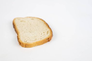 Bir dilim ekmek üzerine beyaz mutfak masası. Haşhaş tohumu parçalar halinde kesilmiş ekmek. Beyaz arka plan.