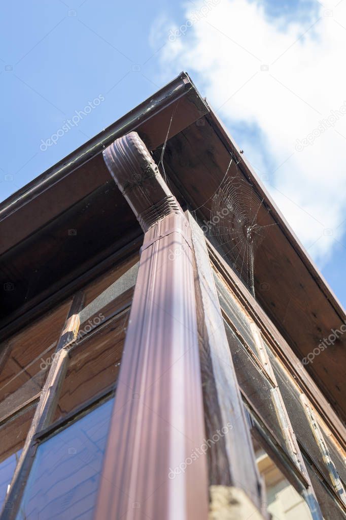 Gutter draining rainwater. The building is equipped with drainage of rainwater from the roof. Season of the summer.