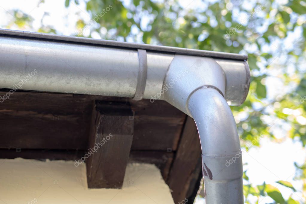 Gutter draining rainwater. The building is equipped with drainage of rainwater from the roof. Season of the summer.