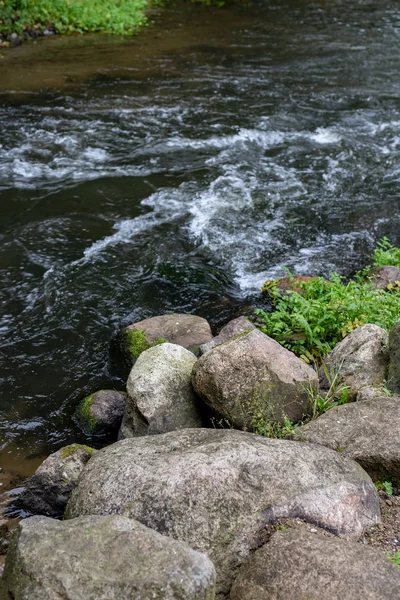 A rushing river flowing in a wooded area. A beautifully wounded hand in the forest. Season of the autumn.