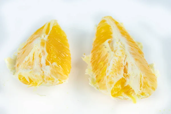 Peeled orange with very thick skin on a white kitchen table. Citruses prepared for desserts. White background.