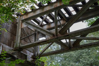Eski kullanılmayan Demiryolu Köprüsü. Bir küçük tren öbür tarafa Orta Avrupa nehirde. Sezon sonbahar.