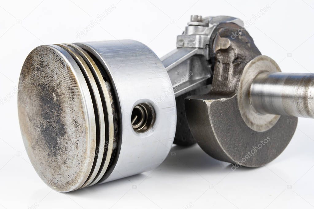 Crankshaft and piston of a small combustion engine on a white table. Spare parts for mechanics. White background.
